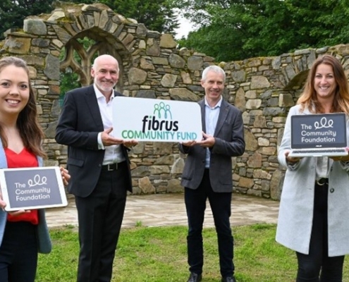 Two men and two women holding signs saying 'Fibrus Community Fund' and 'The Community Foundation'