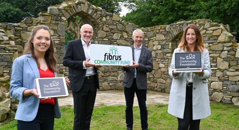 Two men and two women holding signs saying 'Fibrus Community Fund' and 'The Community Foundation'