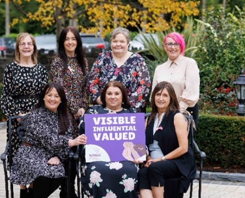 Women holding a sign saying Visible, Influential, Valued.