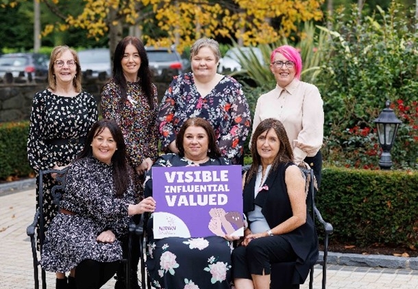 Women holding a sign saying Visible, Influential, Valued.