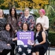 Women holding a sign saying Visible, Influential, Valued.